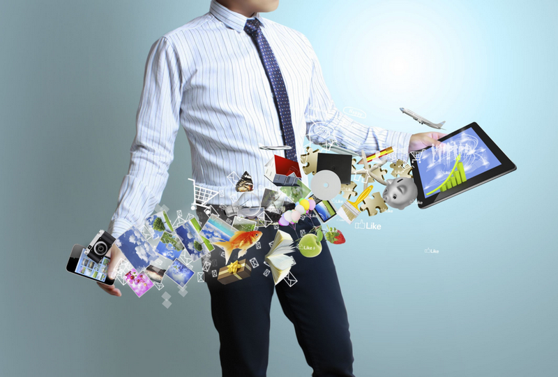 A person in business attire holds a smartphone and tablet with digital icons and images floating between them.