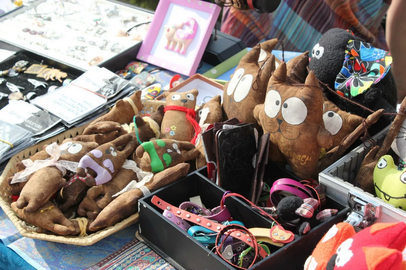 A market stall displaying handmade stuffed animals, various accessories, and jewelry.